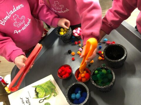 three children playing with coloured pompoms