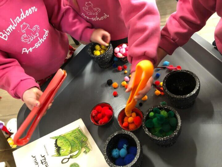 three children playing with coloured pompoms