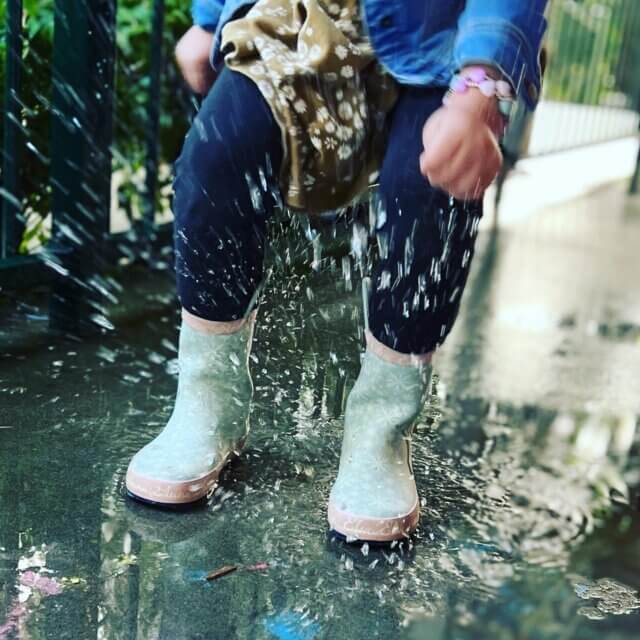 child jumping in water with gum boots
